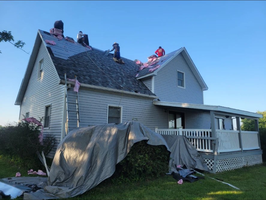 Milo's crew installing new shingles on a two-story farmhouse roof